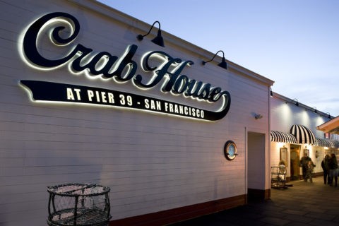 A look at the exterior of Crab House restaurant. White building with a black sign