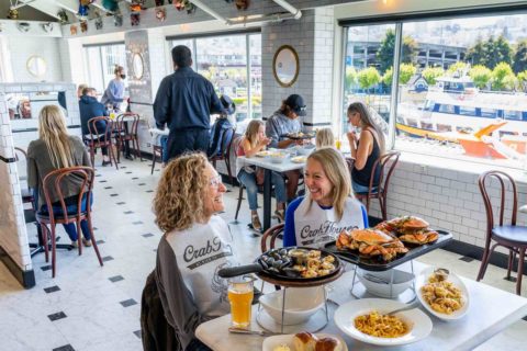 Two women in bibs enjoying a meal at Crab House at PIER 39 seafood restaurant