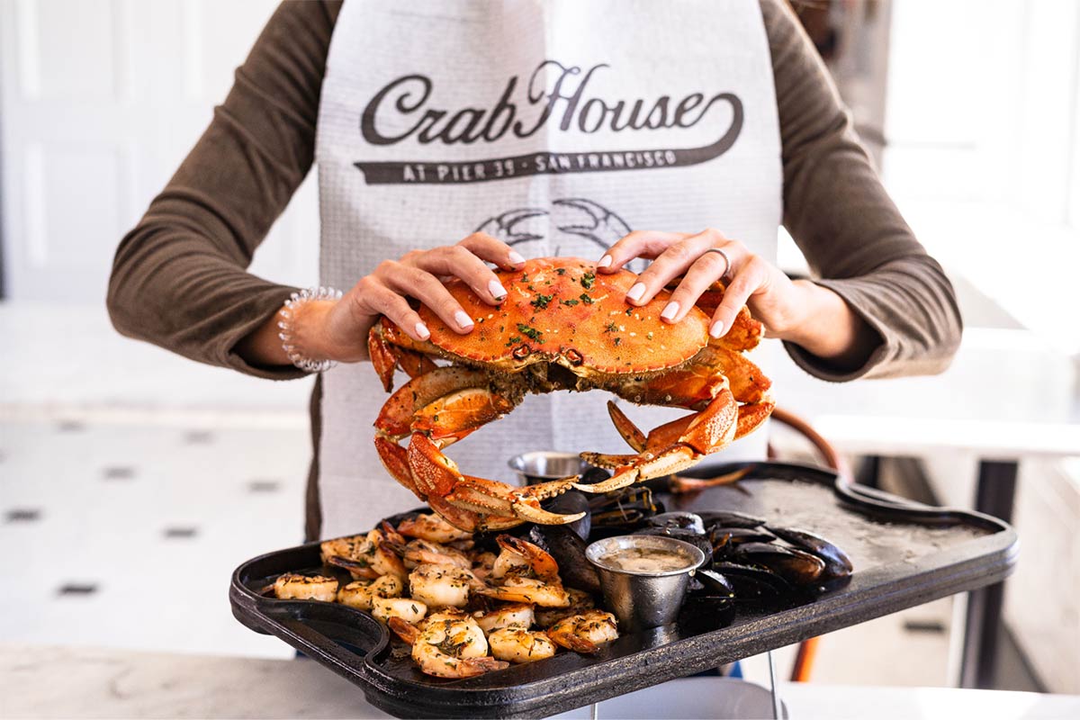 A woman holds a whole Dungeness crab at Crab House at Pier 39 in Fisherman’s Wharf